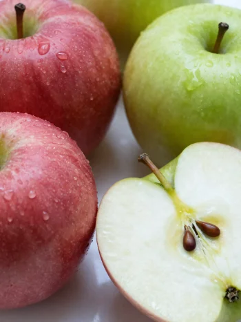 Pommes fraîches rouges et vertes sur planche à découper, tranchées et entières, avec jus