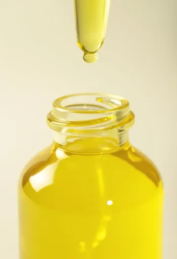 Flacon d'huile de citron avec tranches de citron fraîches et zestes