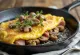 Omelette aux champignons et jambon fumé, servie avec du persil frais