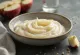 Purée ail-pomme dans un bol en céramique, entourée de pommes et gousses d'ail