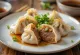 Jiaozi chinois au canard laqué bouilli, sur assiette blanche, farce au canard visible