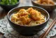 Karaage udon servi en bol avec poulet frit, sauce soja et oignon vert frais