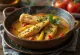 Moqueca avec morceaux de poisson, poivrons rouges et jaunes, servie dans une sauce au lait de coco
