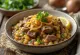 Haleem aux oignons frits, servi avec épices riches et coriandre fraîche